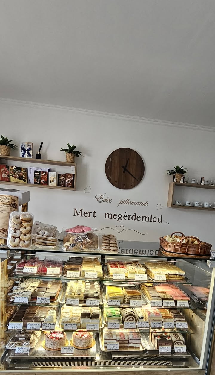 A cukrászda vitrinje szeletes süteményekkel, fánkokkal és tortákkal.